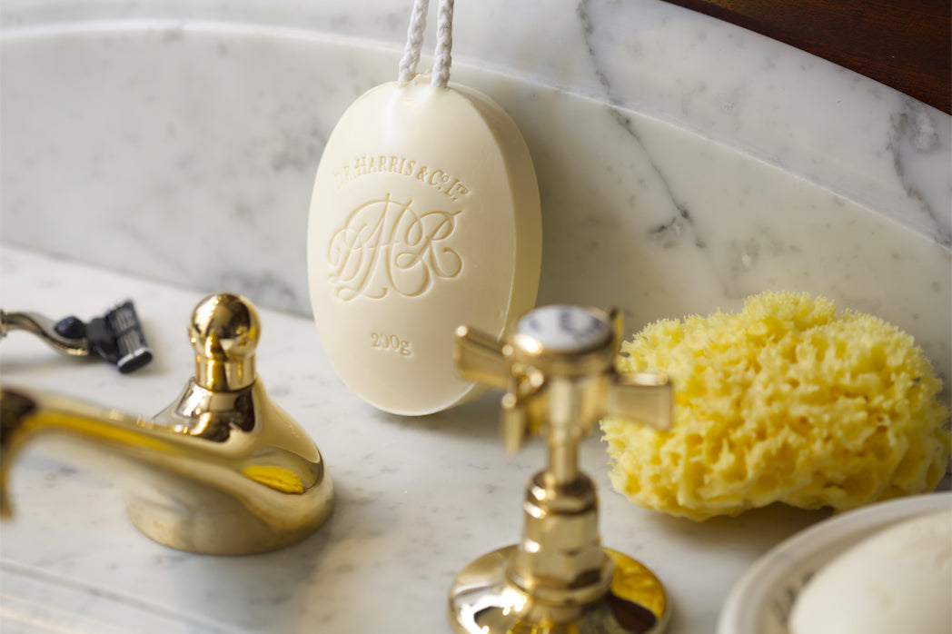 Arlington Soap on a Rope next to a Natural Sponge and Manual Razor, on a Marble Sink